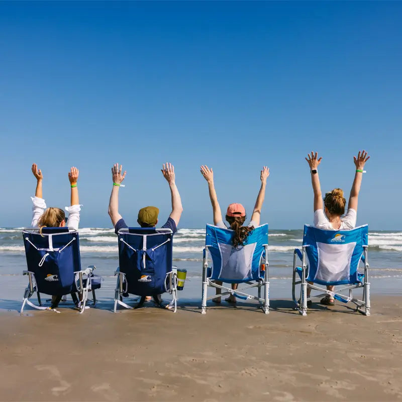 Group of friends raising their arms while sitting in Saybrook Blue Beach Rockers on the beach.