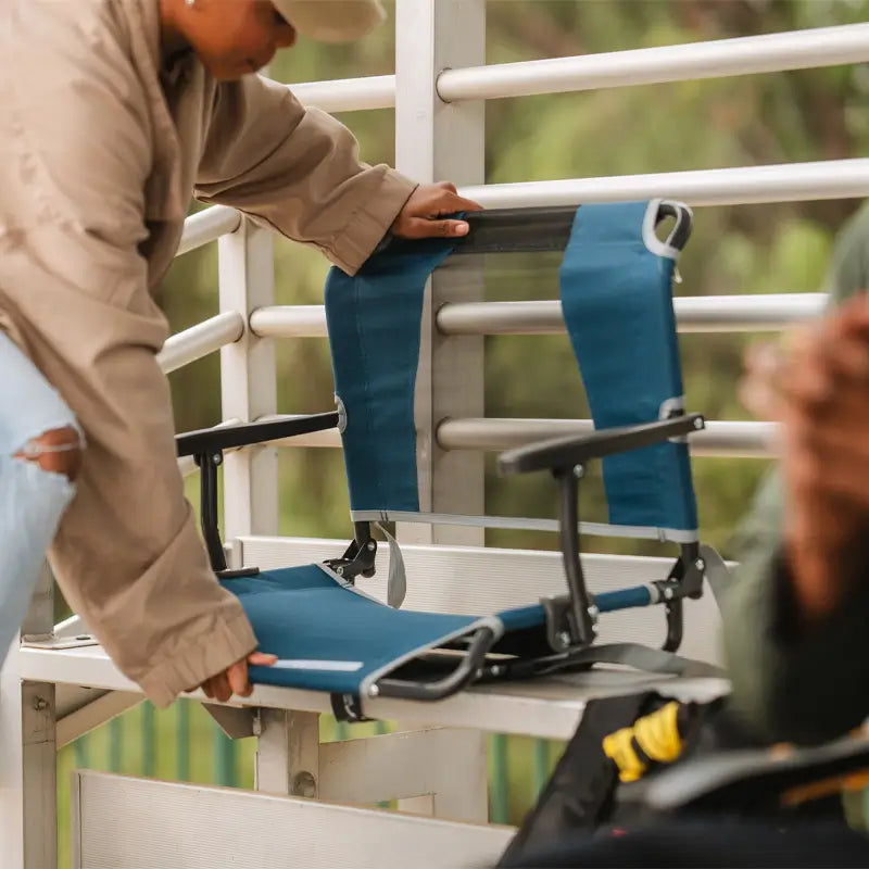 all-groups, Person setting up the Big Comfort Stadium Seat on aluminum bleachers.