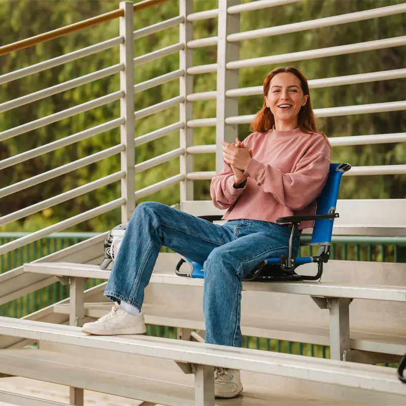 all-groups, Woman smiling and applauding while seated in a Big Comfort Stadium Seat on metal bleachers.