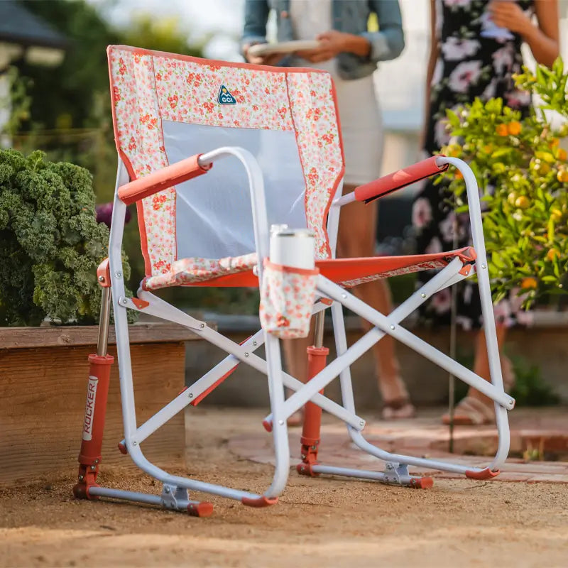 Freestyle Rocker with red floral print and drink holder sits near a raised garden bed.