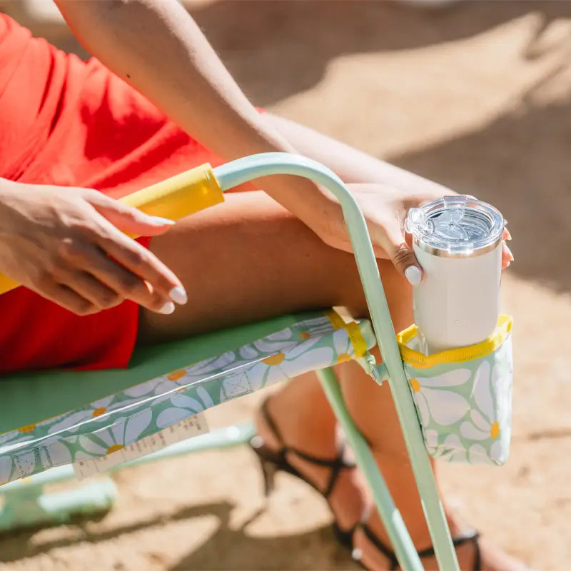 Close-up of a white tumbler in the side cupholder of a floral Freestyle Rocker.