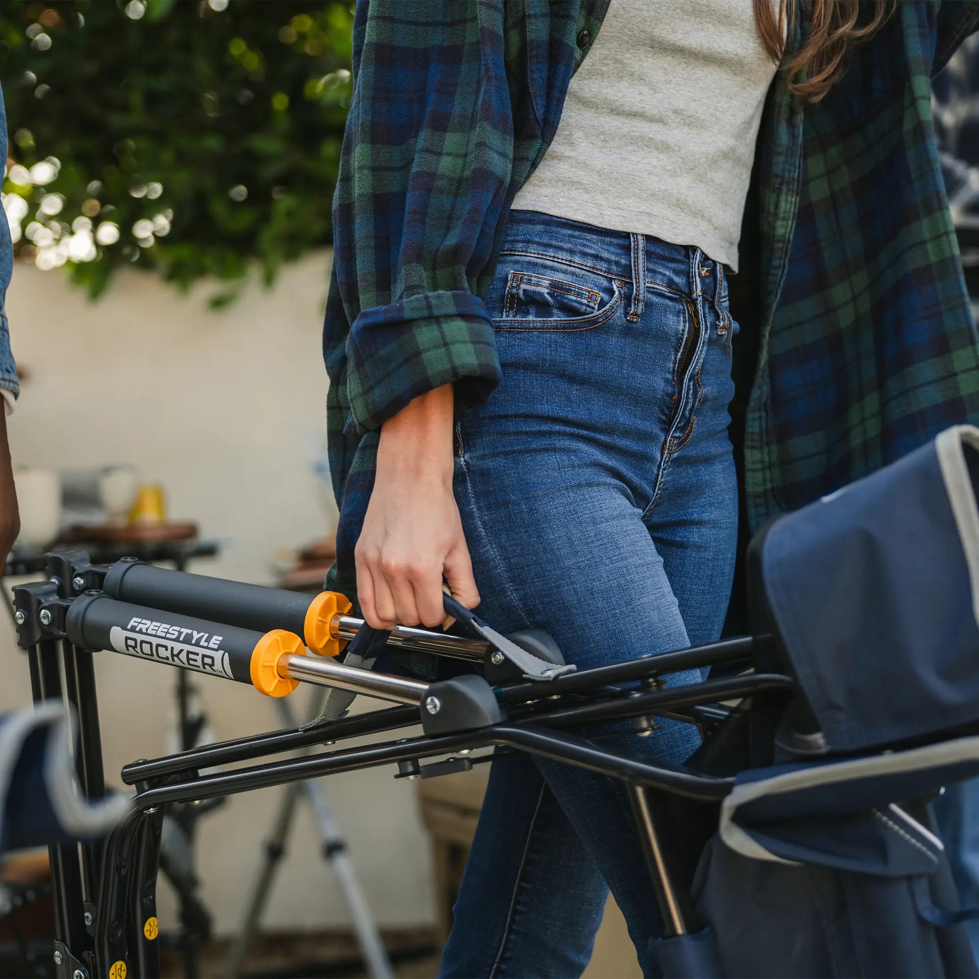 An up-close shot of a woman carrying an indigo freestyle rocker using the integrated carry handle.