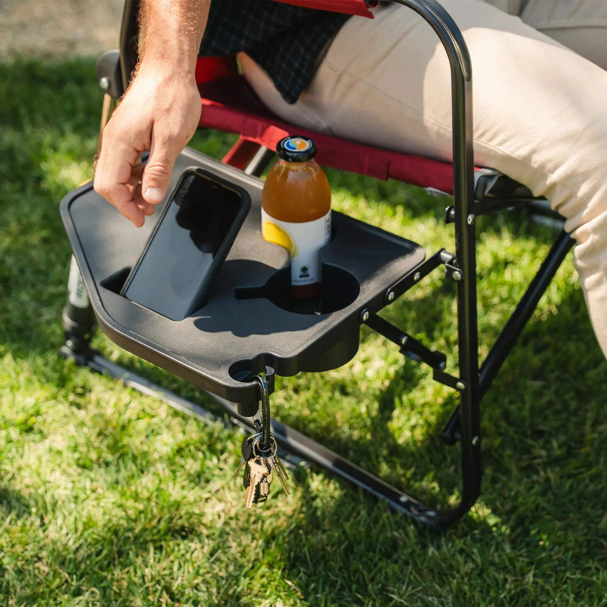 A man grabbing for his phone that is positioned in the side table of a freestyle rocker xl with side table.