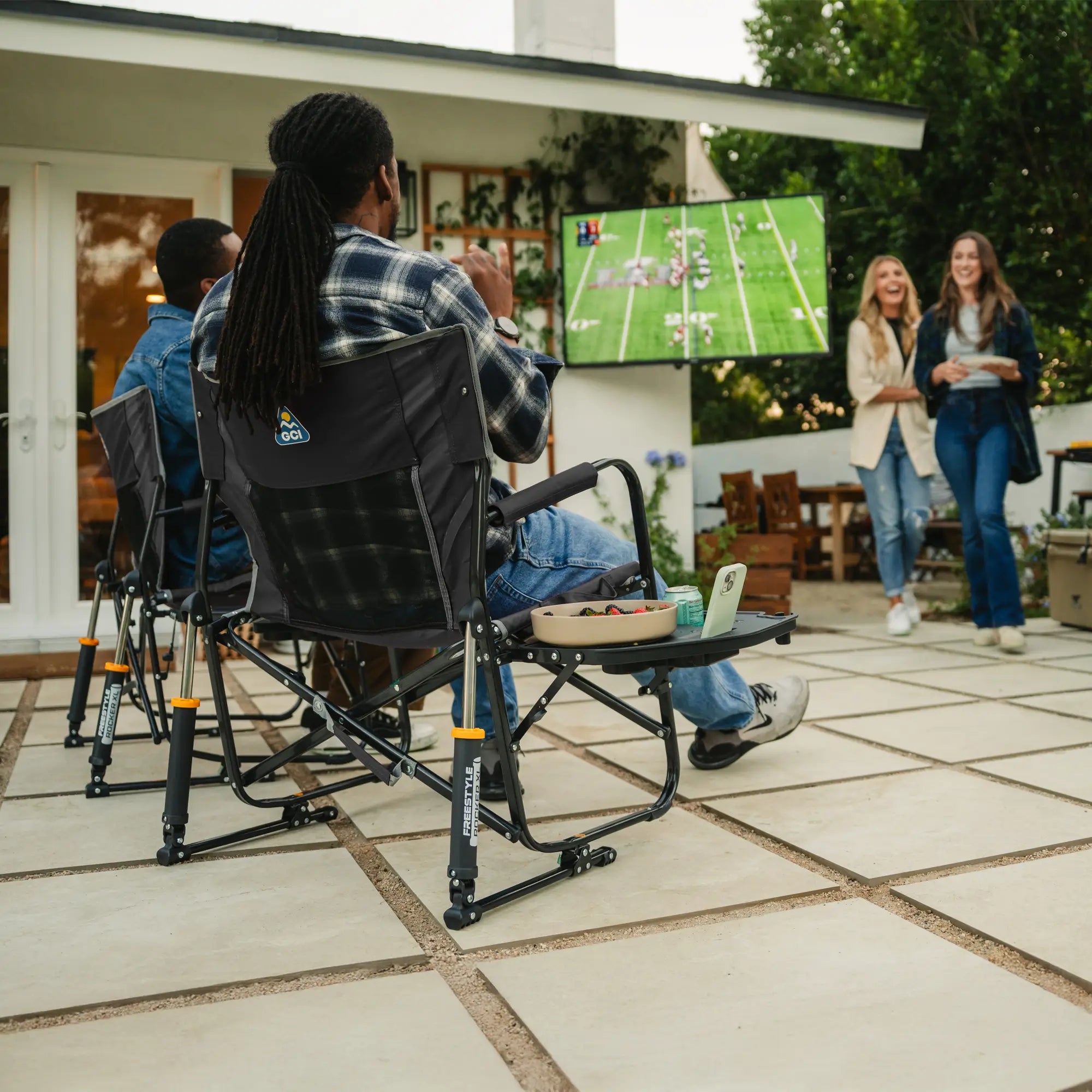 Two people cheering while watching a football game in their freestyle rocker xl with side table chairs. 