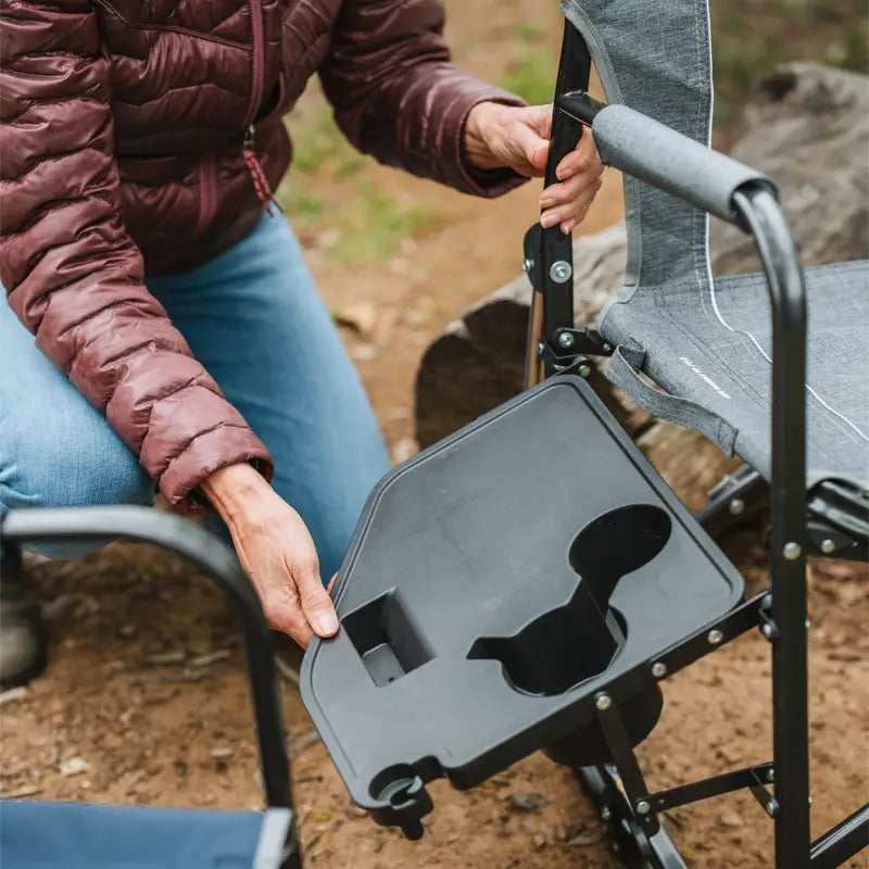 Close-up of woman attaching a black plastic side table to the Freestyle Rocker.