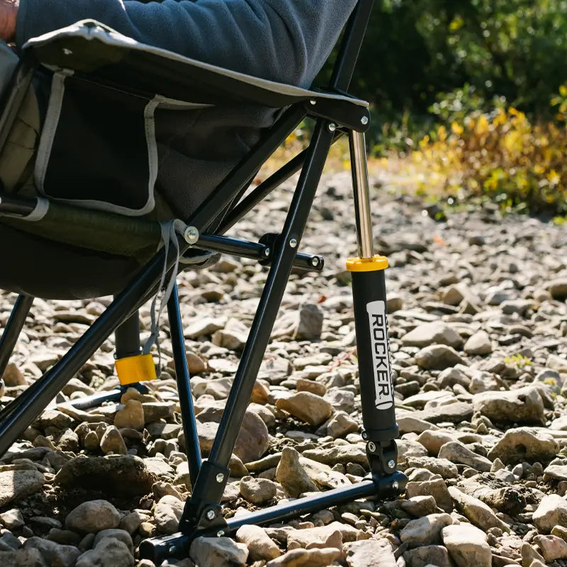 Close-up of the heathered loden Kickback Rocker leg on rocky terrain, showing the "ROCKER" logo and sturdy frame.