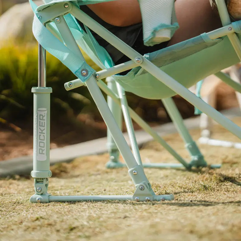 Side view of the pastel green leaf Kickback Rocker’s frame and rocker mechanism on grass.