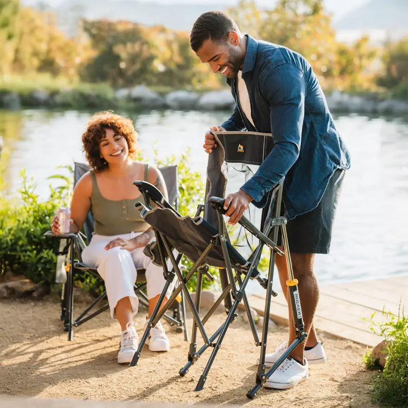 Man unfolding the indigo RoadTrip Rocker while a woman watches and smiles.