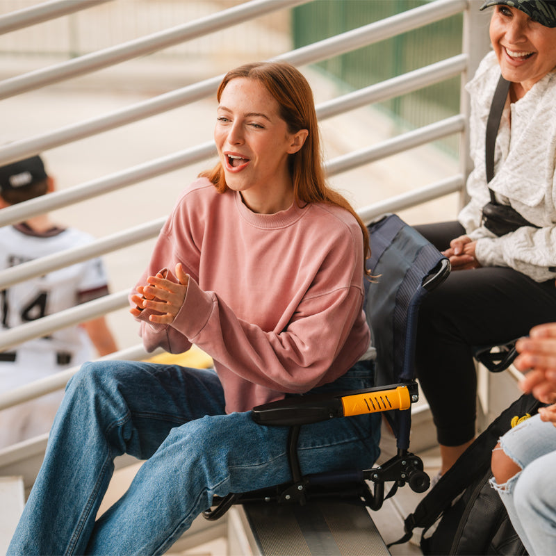 Woman cheering on bleachers while seated in a rich blue Stadium Rock-Cliner.